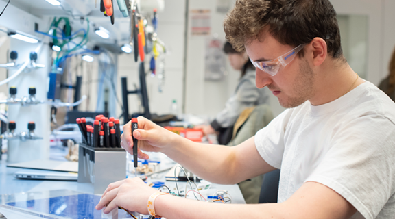 student in lab working on electronics