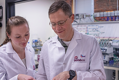 Mary Clare McCorry and her boss, ARMI | BioFabUSA CTO Tom Bollenbach, at the Advanced Regenerative Manufacturing Institute (ARMI) in front of the tissue manufacturing line she helped to build.