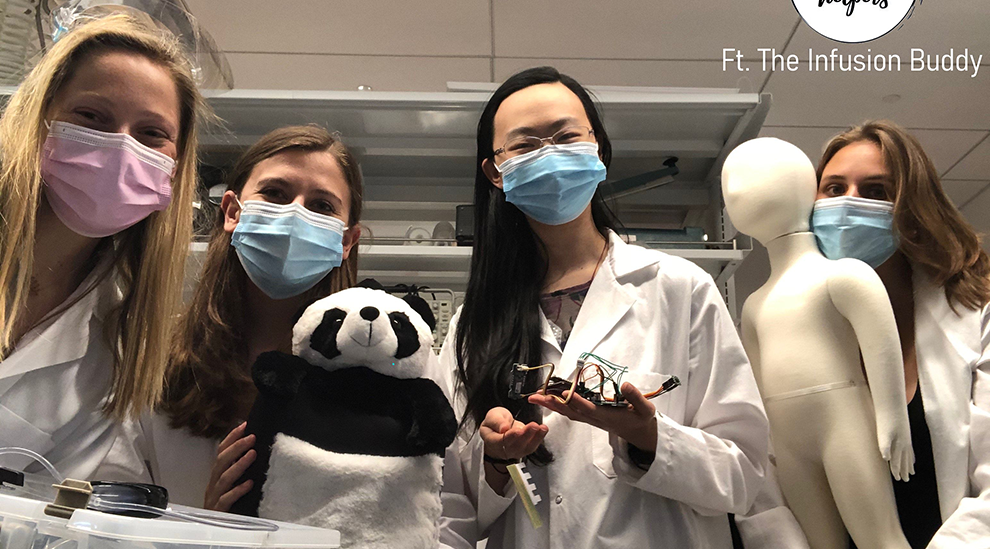 four students in lab coats holding panda backpack and child mannequin
