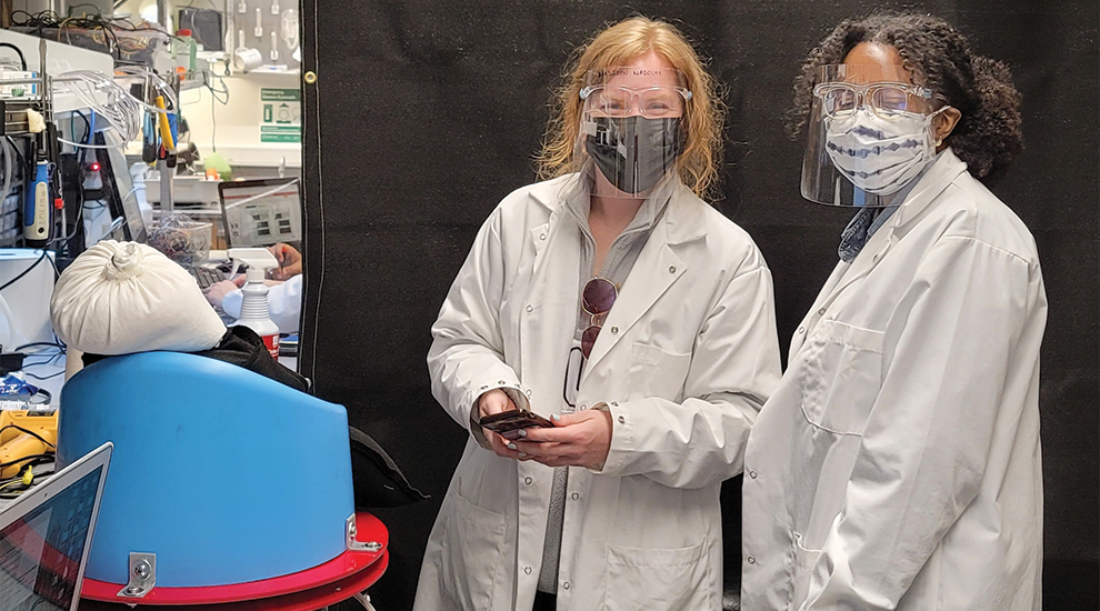 two students in lab coats in the lab