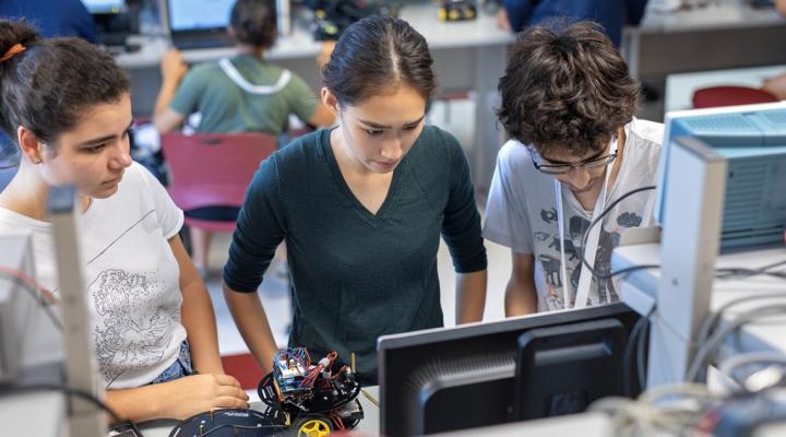 Teaching assistant Megan Backus ’21, center, helps two CATALYST Academy participants with coding in 2018.